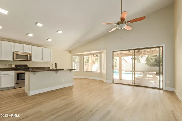 a open kitchen with granite countertop a stove top oven a sink and white cabinets with wooden floor