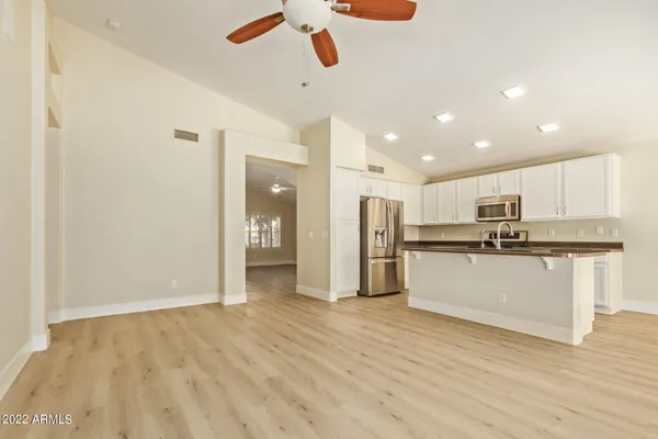 a view of kitchen with stainless steel appliances refrigerator stove microwave and white cabinets