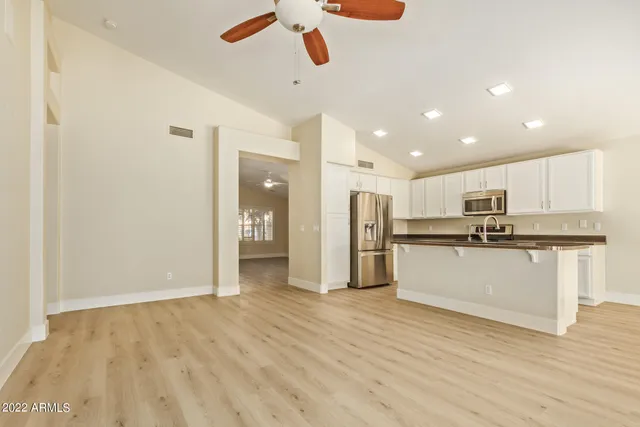a view of kitchen with stainless steel appliances refrigerator stove microwave and white cabinets