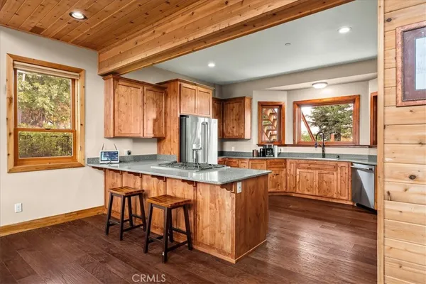 a kitchen with stainless steel appliances granite countertop a refrigerator a stove and a wooden floors