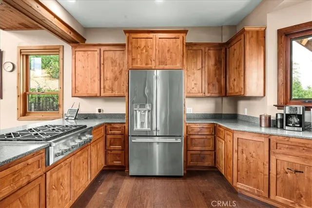 a kitchen with granite countertop wooden floors stainless steel appliances a sink and a window