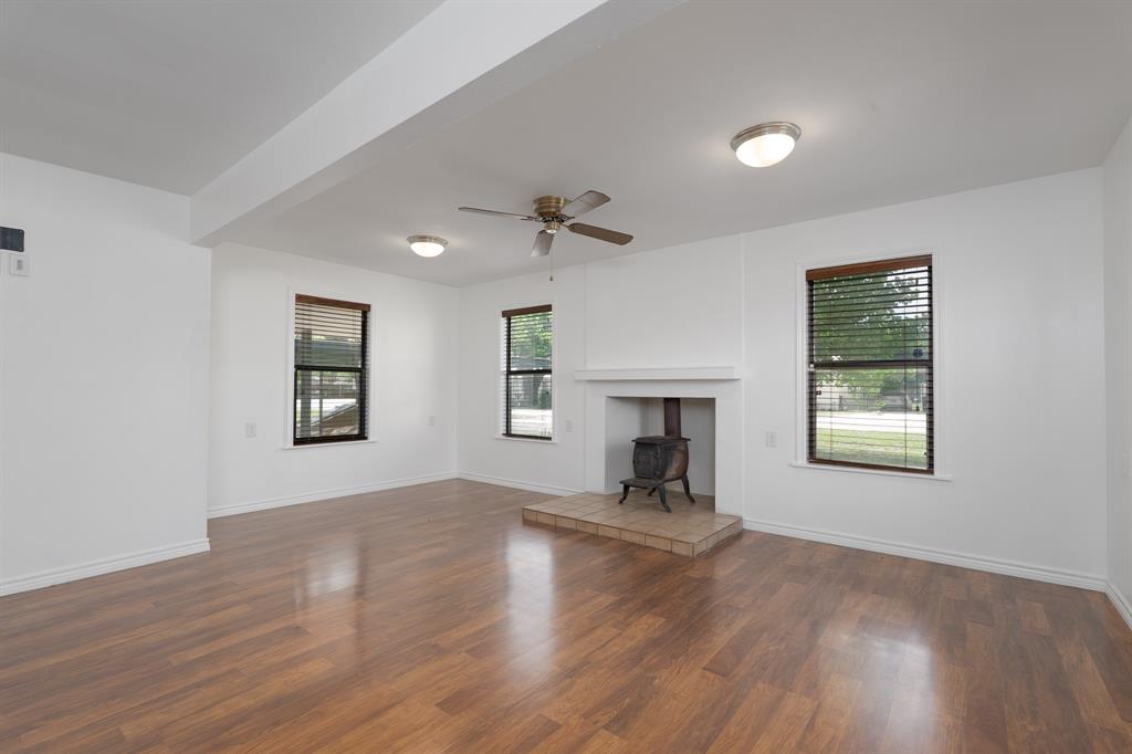 809 Turner Lane Tuscola, TX 79562 - Photo 17 of 25 Unfurnished living room with a wood stove, dark wood finished floors, and a ceiling fan
