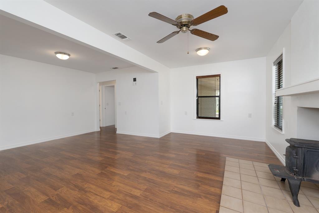 809 Turner Lane Tuscola, TX 79562 - Photo 19 of 25 Unfurnished living room with a wood stove, wood finished floors, and ceiling fan