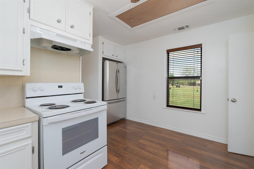 809 Turner Lane Tuscola, TX 79562 - Photo 23 of 25 Kitchen with white range with electric cooktop, under cabinet range hood, freestanding refrigerator, dark wood-style flooring, and white cabinets