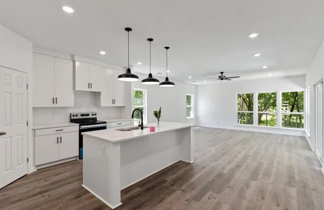 a kitchen with stainless steel appliances granite countertop a sink a stove and a wooden floors