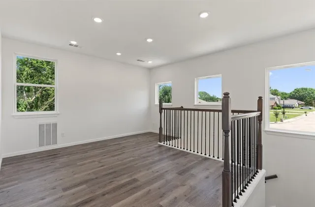 a view of a hallway with wooden floor and windows