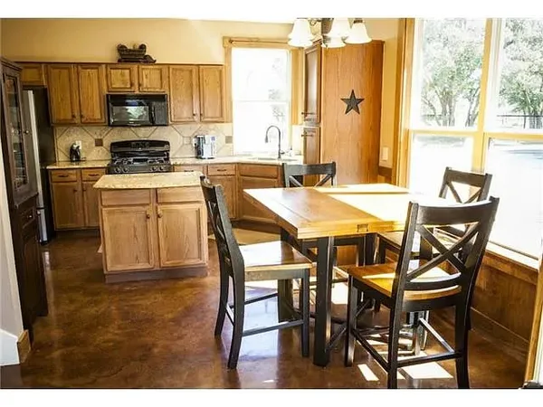 a kitchen with stainless steel appliances granite countertop a stove a refrigerator a microwave and a dining table
