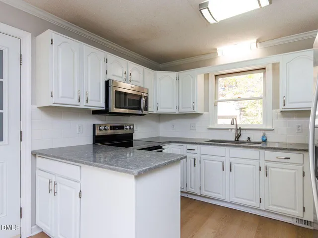 a kitchen with granite countertop white cabinets and a window