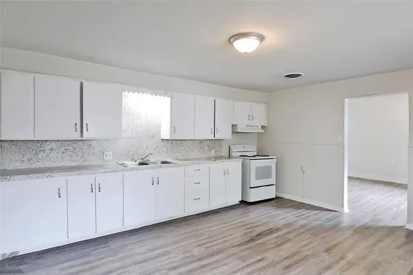 a kitchen with granite countertop white cabinets and white stainless steel appliances