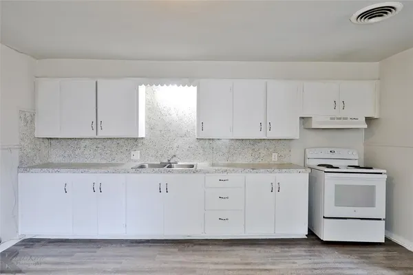 a kitchen with granite countertop white cabinets and a stove