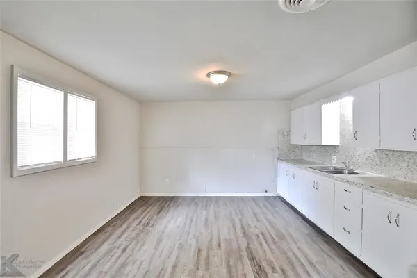 a view of a kitchen with wooden floor and electronic appliances