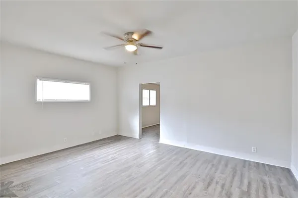 an empty room with wooden floor and window
