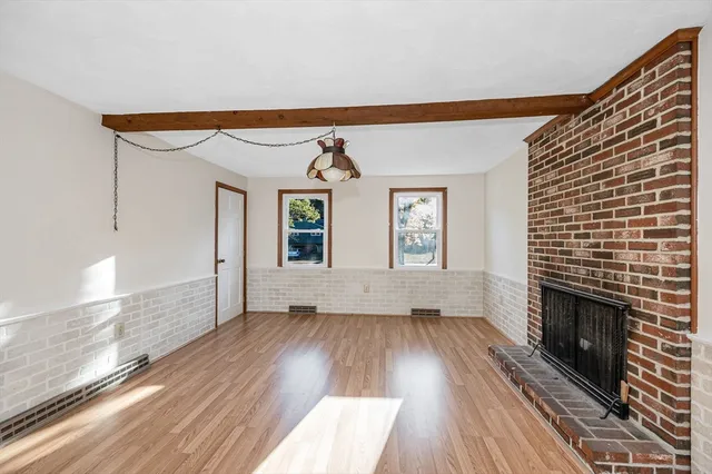 a view of empty room with wooden floor and fireplace