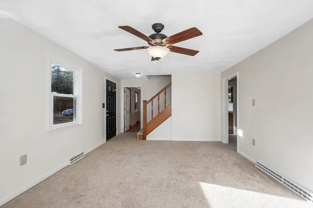 a view of an empty room with window and ceiling fan