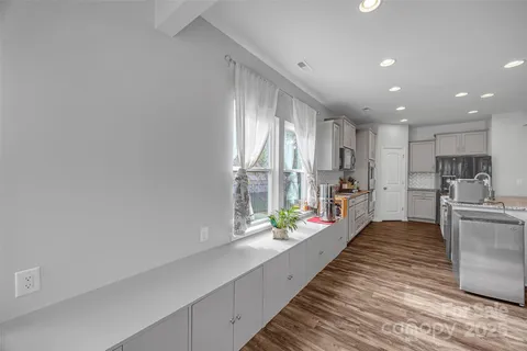 a large white kitchen with large windows and refrigerator