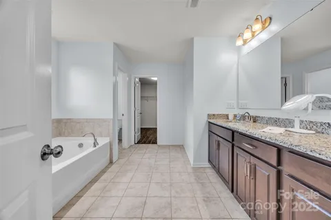 a spacious bathroom with a granite countertop tub a double vanity sink and a mirror