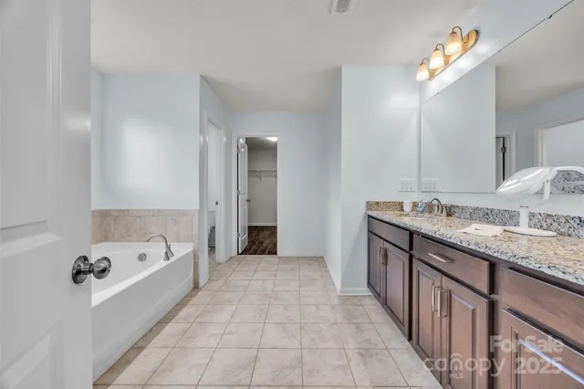 a spacious bathroom with a granite countertop tub a double vanity sink and a mirror