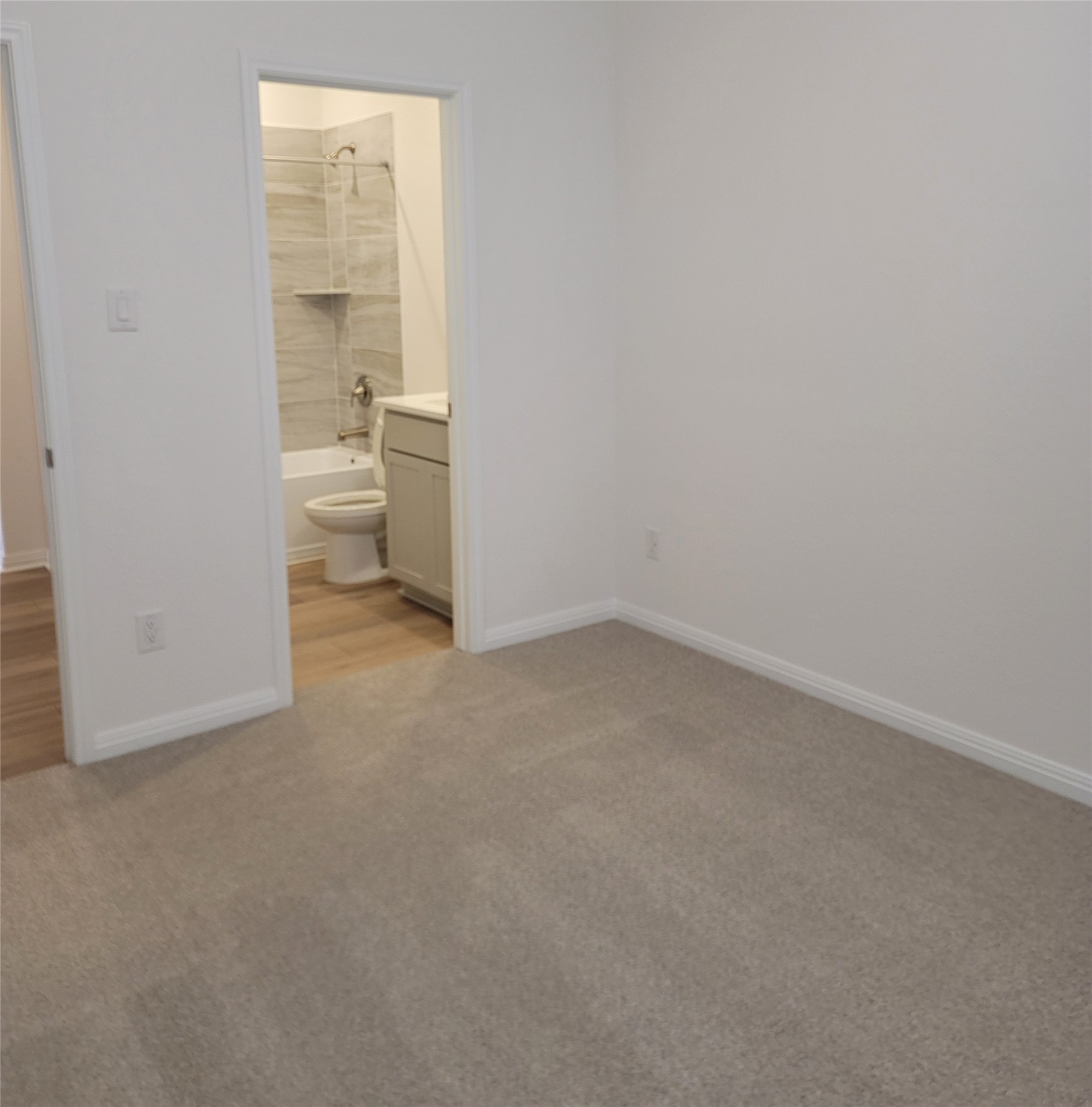 200 Callahan Loop Buda, TX 78610 - Photo 12 of 13 Carpeted room with white walls, baseboards, and a doorway opening to a bathroom