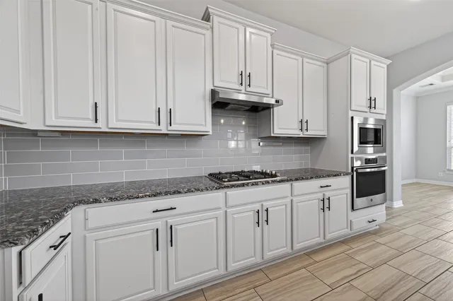 a kitchen with granite countertop white cabinets and a stainless steel appliances