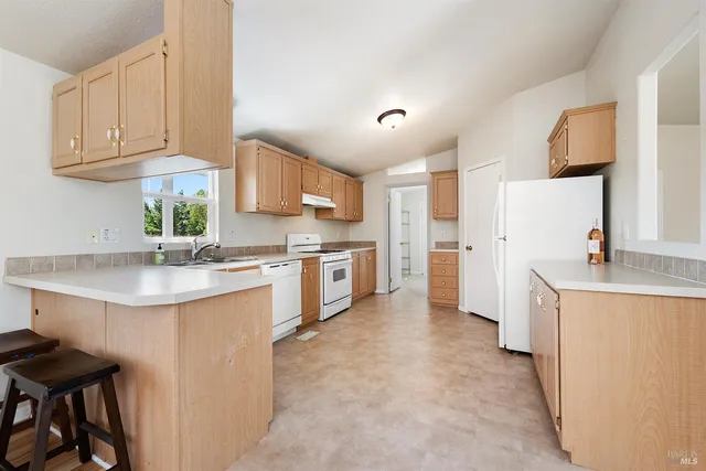 a kitchen with granite countertop a sink cabinets stainless steel appliances and a window