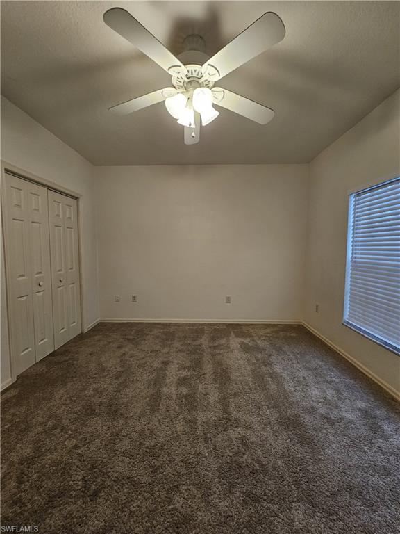 6025 Chardonnay Lane, Unit 102 Naples, FL 34119 - Photo 29 of 37 an empty room with a chandelier fan and windows