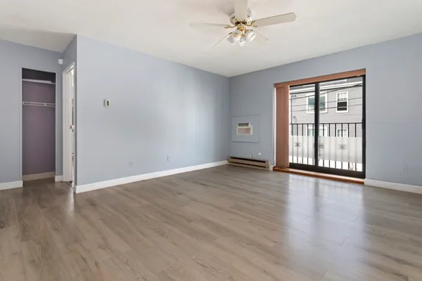 a view of an empty room with wooden floor and a window
