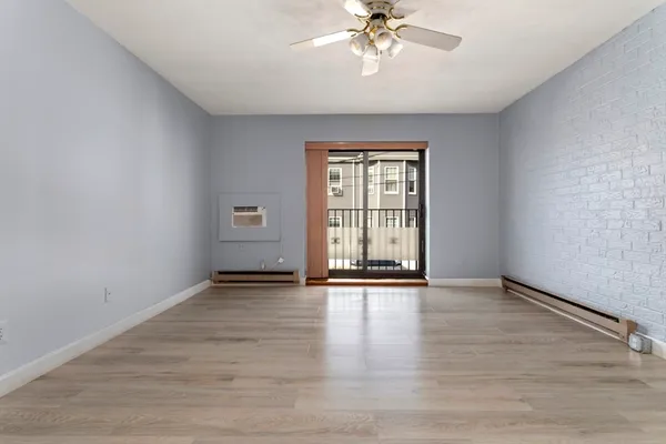 a view of an empty room with a window and wooden floor