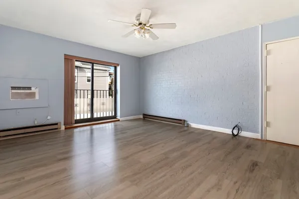 an empty room with wooden floor chandelier fan and windows