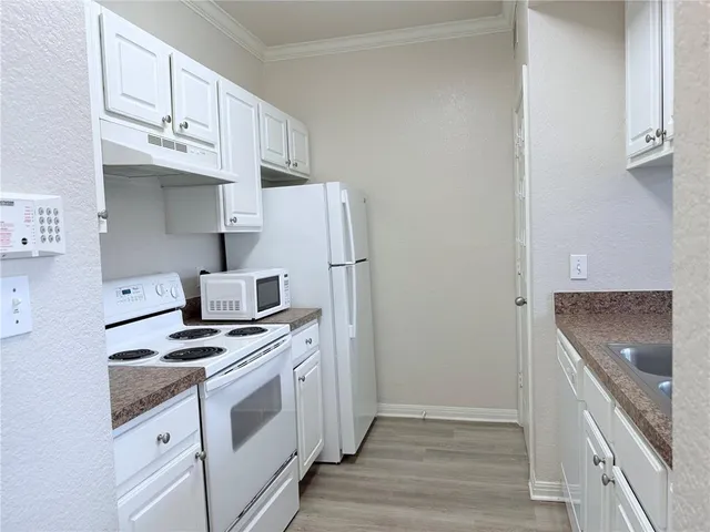 a kitchen with stainless steel appliances a refrigerator a stove and white cabinets