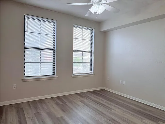 an empty room with wooden floor and windows