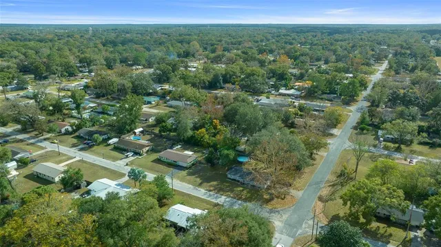an aerial view of residential houses with outdoor space and trees