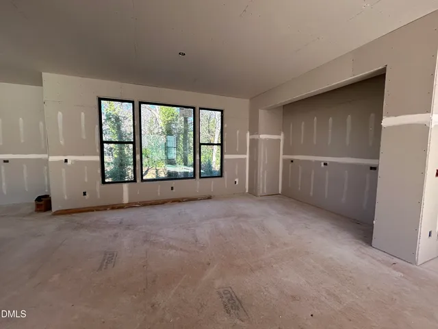 an empty room with chandelier fan and windows