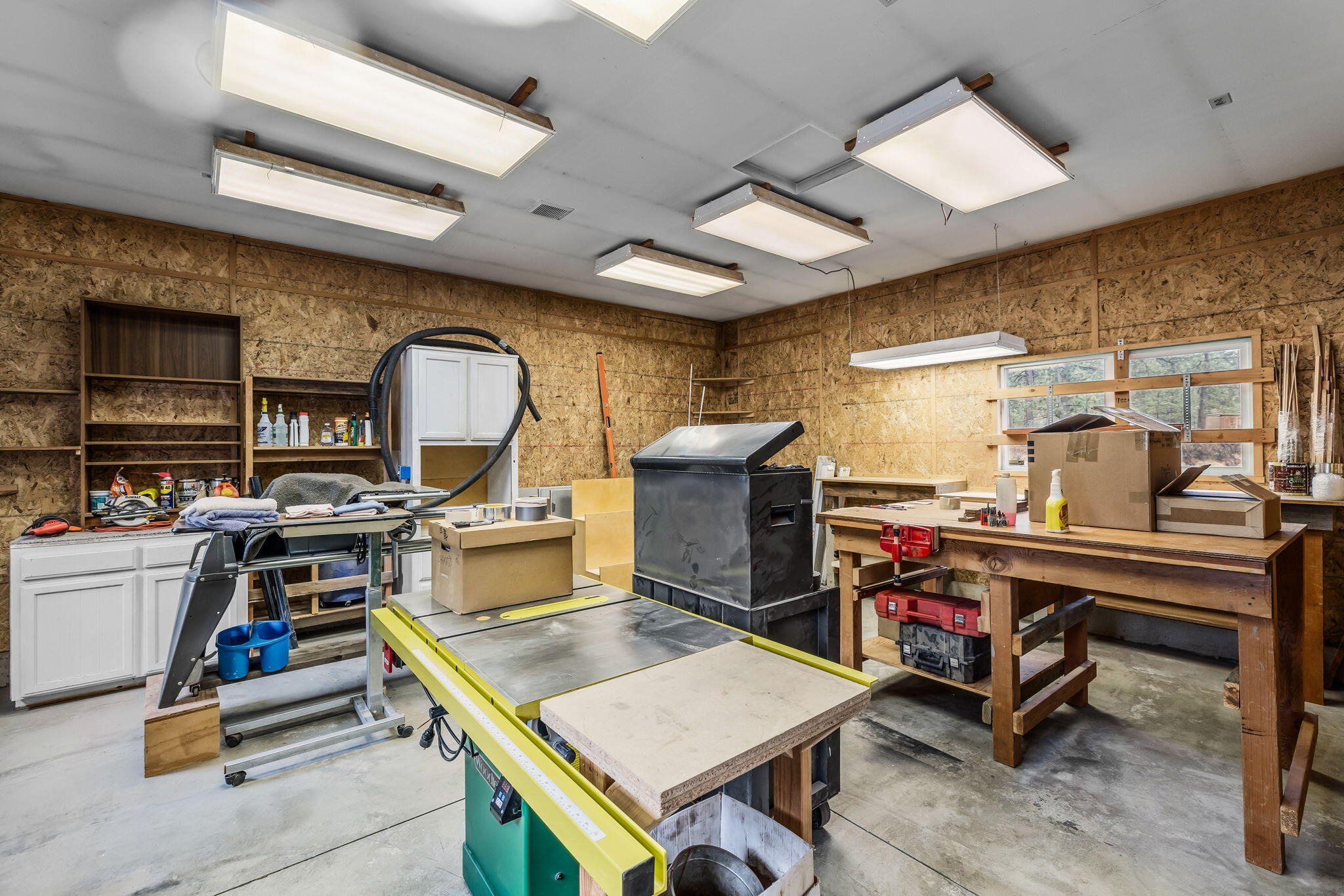 60290 Woodside Loop Bend, OR 97702 - Photo 7 of 47 Attached large insulated shop with 50 amp service and thermostat controlled pellet stove, concrete flooring, workbench, ceiling exhaust fans, cabinets and shelving.