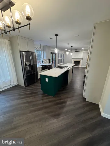 a kitchen with stainless steel appliances granite countertop a refrigerator a sink dishwasher a stove and a dining table with wooden floor