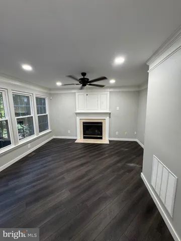 a view of an empty room with wooden floor fireplace and a window
