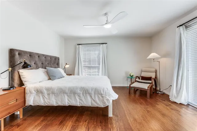 a bedroom with a bed a lamp and wooden floor