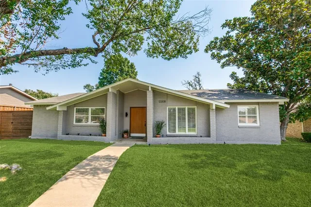 a view of a house with a yard and large trees