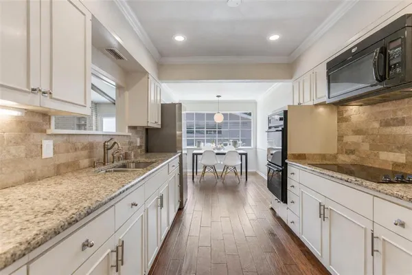 a large kitchen with stainless steel appliances granite countertop a lot of counter space and wooden floor
