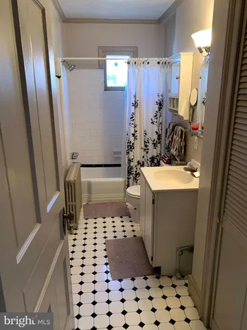 a bathroom with a sink a toilet a window and shower