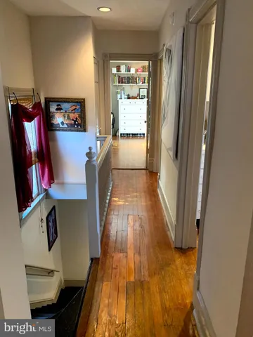 a view of a hallway with wooden floor and furniture
