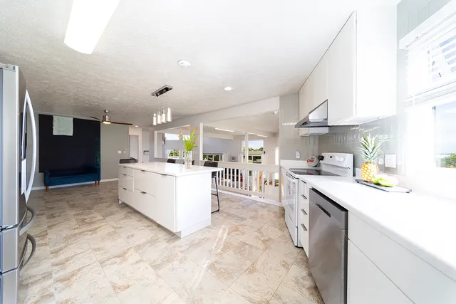 a large kitchen with stainless steel appliances kitchen island granite countertop a sink counter space and a view of living room