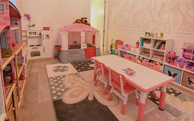 a view of a patio with couches table and chairs under an umbrella with large trees