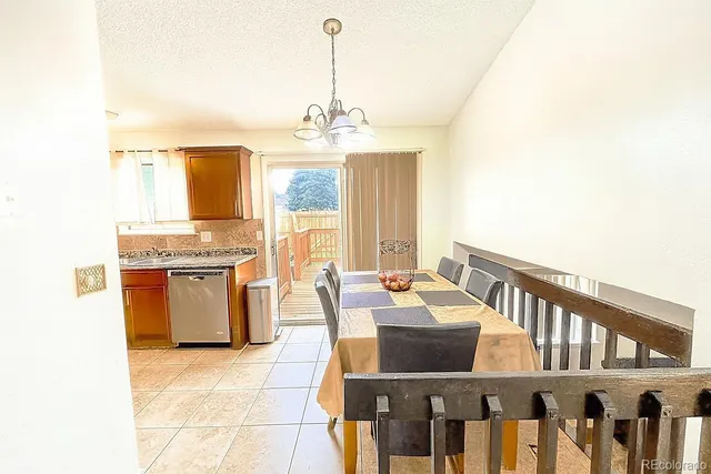 a living room with stainless steel appliances kitchen island granite countertop furniture and a chandelier