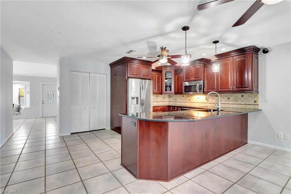 3035 42nd Terrace Southwest Naples, FL 34116 - Photo 35 of 48 Kitchen featuring a peninsula, stainless steel appliances, ceiling fan, and decorative light fixtures