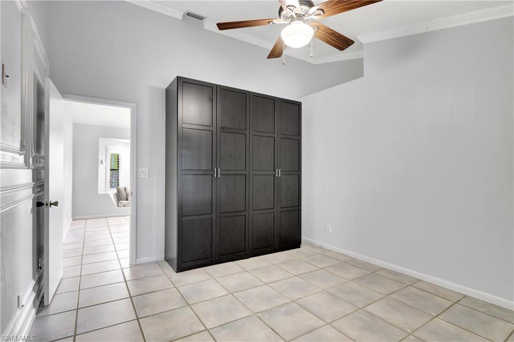 3035 42nd Terrace Southwest Naples, FL 34116 - Photo 37 of 48 Master bedroom featuring ornamental molding, ceiling fan, light tile patterned floors, and a closet