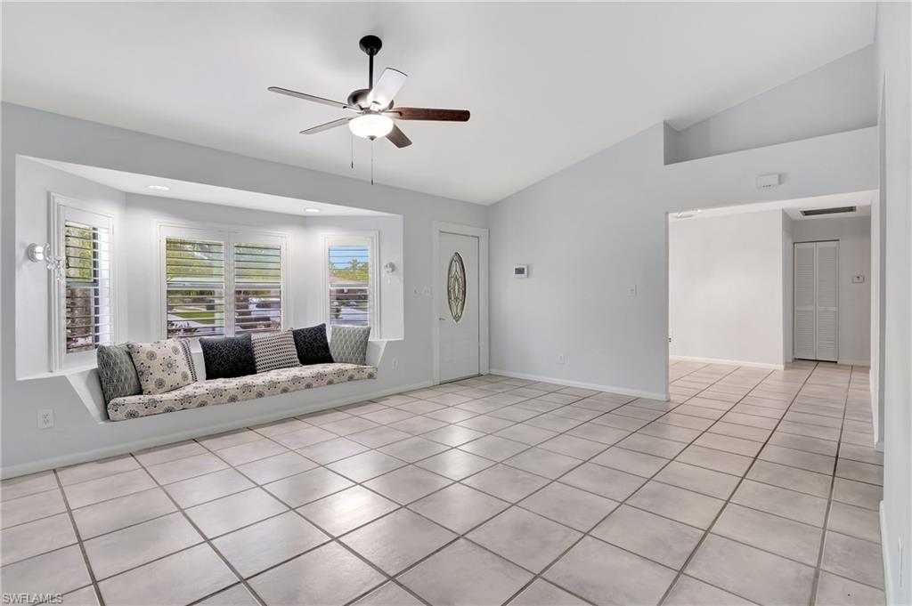 3035 42nd Terrace Southwest Naples, FL 34116 - Photo 8 of 48 Unfurnished living room with ceiling fan, light tile patterned flooring, and lofted ceiling.