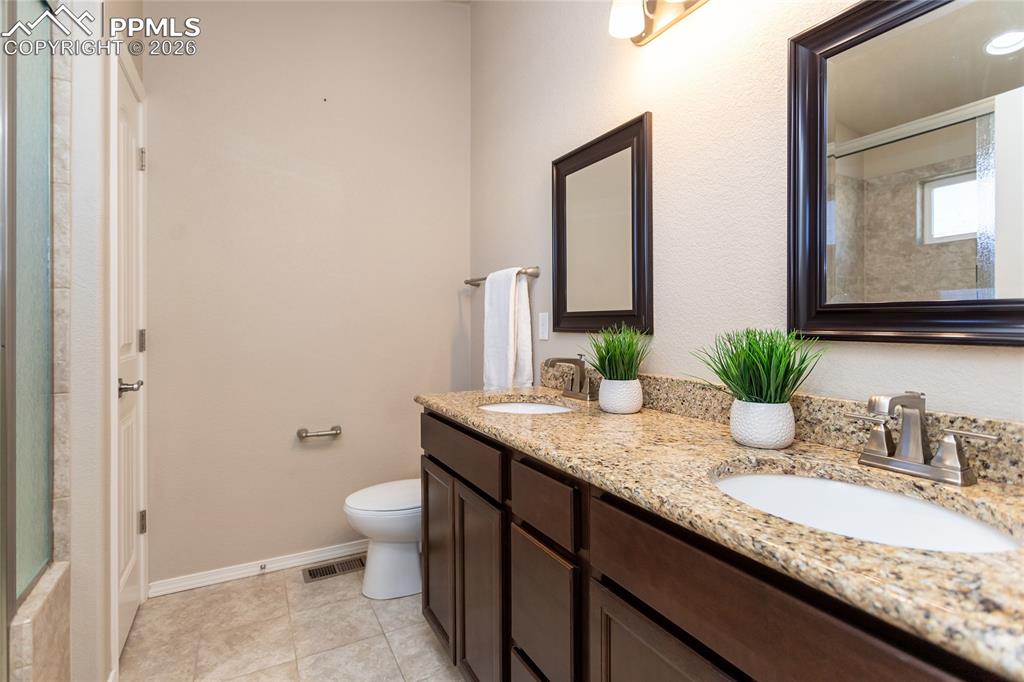 1534 York Road Colorado Springs, CO 80920 - Photo 28 of 38 a bathroom with a granite countertop sink a toilet and mirror