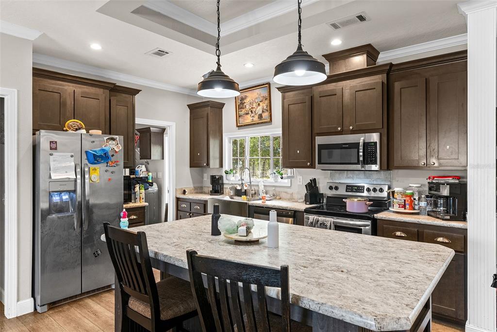 8010 Palmer Road Bartow, FL 33830 - Photo 8 of 22 a kitchen with stainless steel appliances granite countertop a refrigerator a stove top oven a sink a center island and chairs