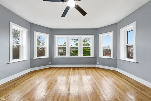 a view of an empty room with window and a kitchen