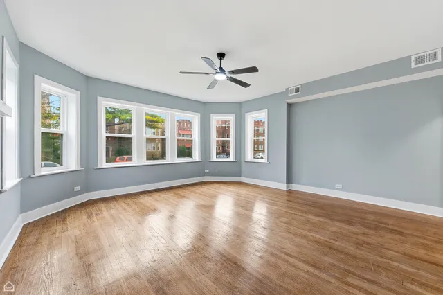 a view of empty room with wooden floor and fan